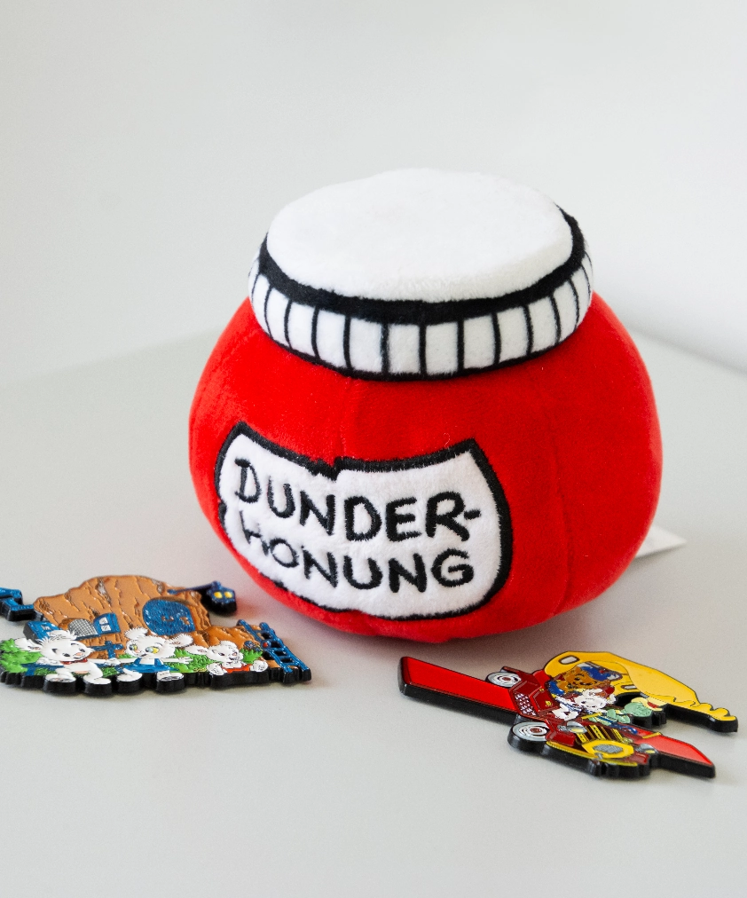 En närbild på Färjestad BK merchandise: ett beigefärgat tyg med broderat klubbmärke och "KARLSTAD", ett golfklubbsfodral och en mugg