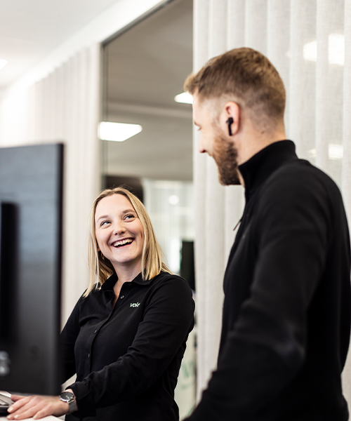 Två Voky-anställda ler mot varandra med en dator framför sig